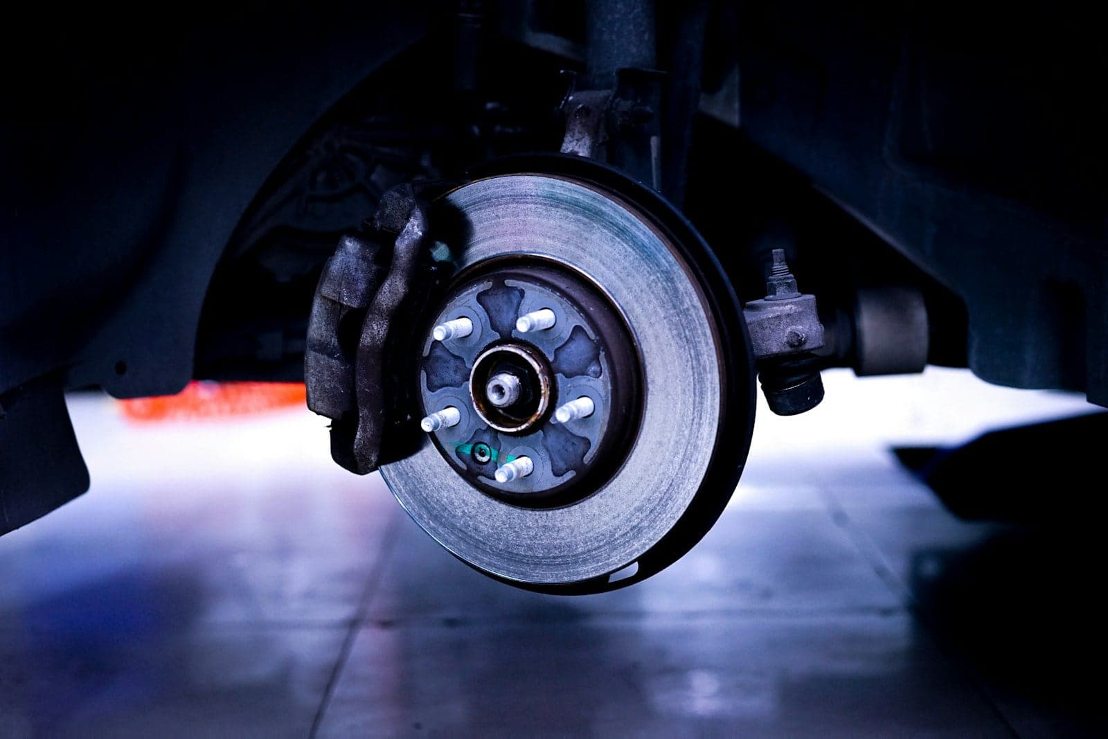 Brake disc and caliper exposed on a car raised on a workshop lift