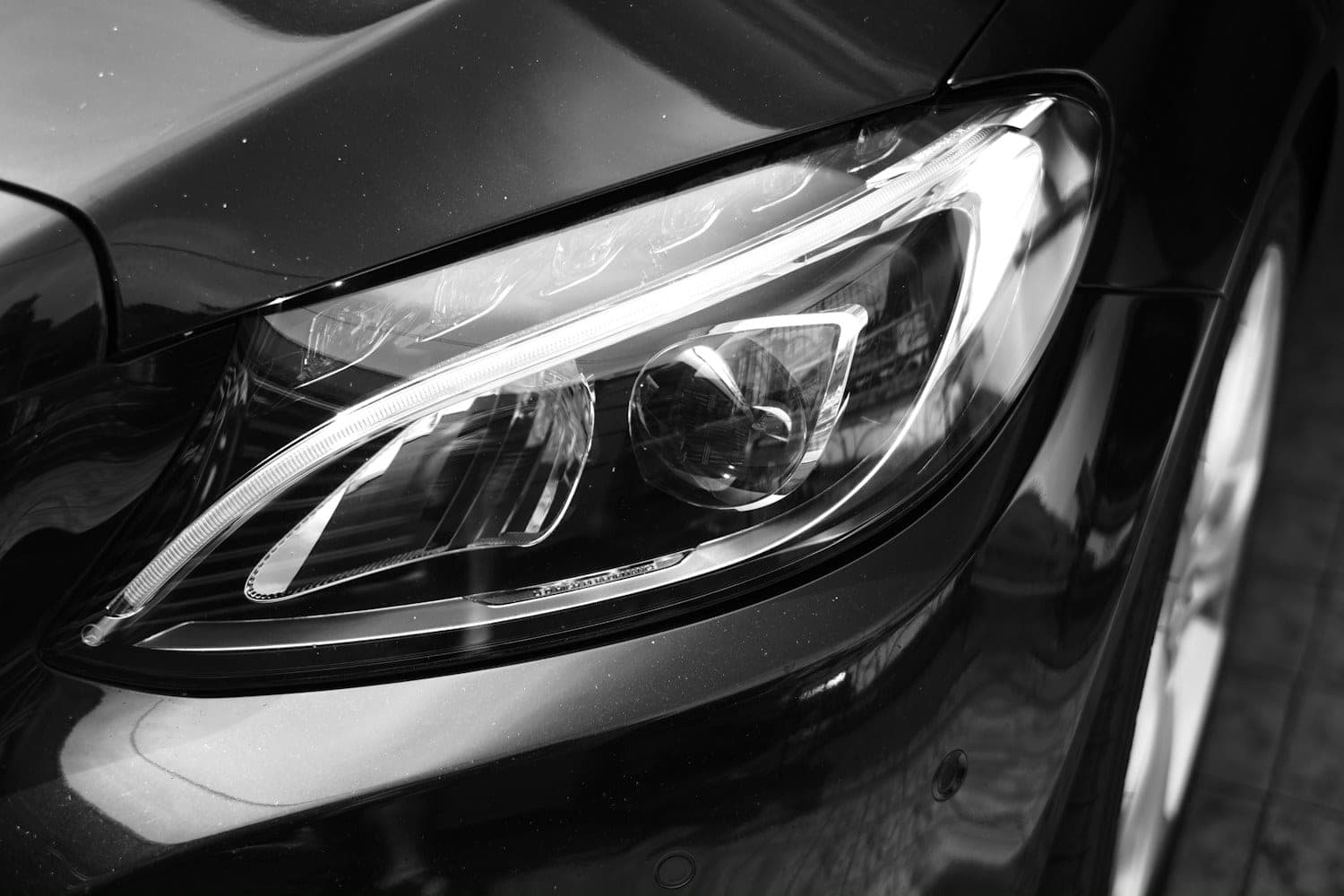Close-up of the LED headlight on a dark car, photographed in black and white