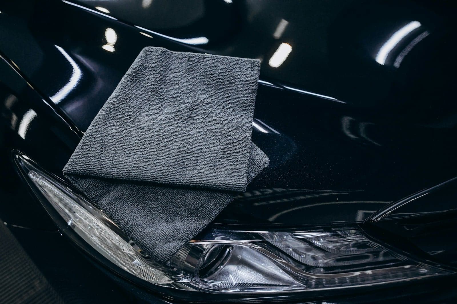 Gray microfiber towel folded on the polished hood of a black car