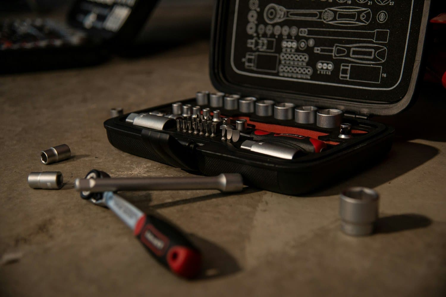 Open socket set and a ratchet laid out on a garage floor