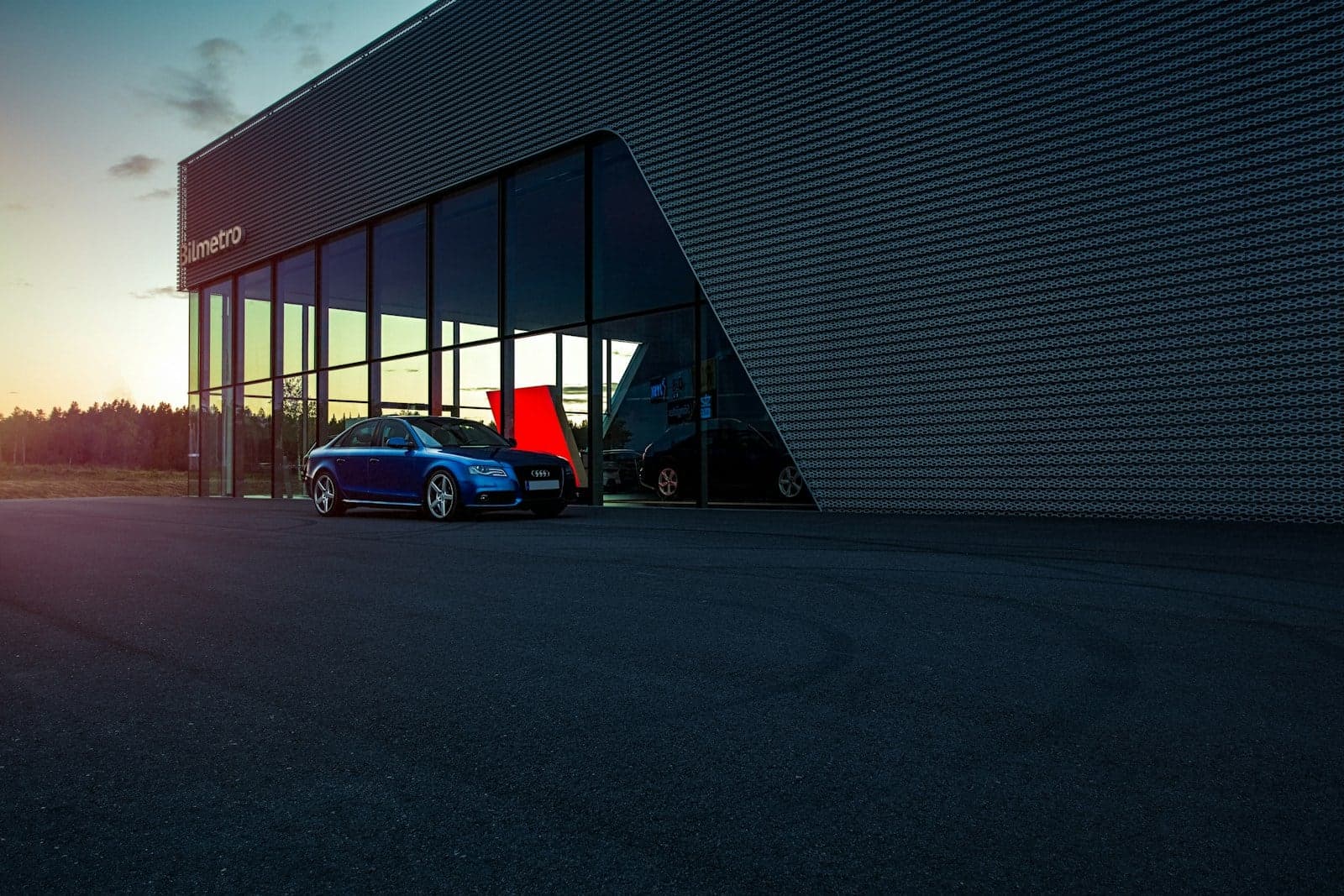 Car showroom at dusk Blue car parked outside a glass-fronted car showroom at dusk