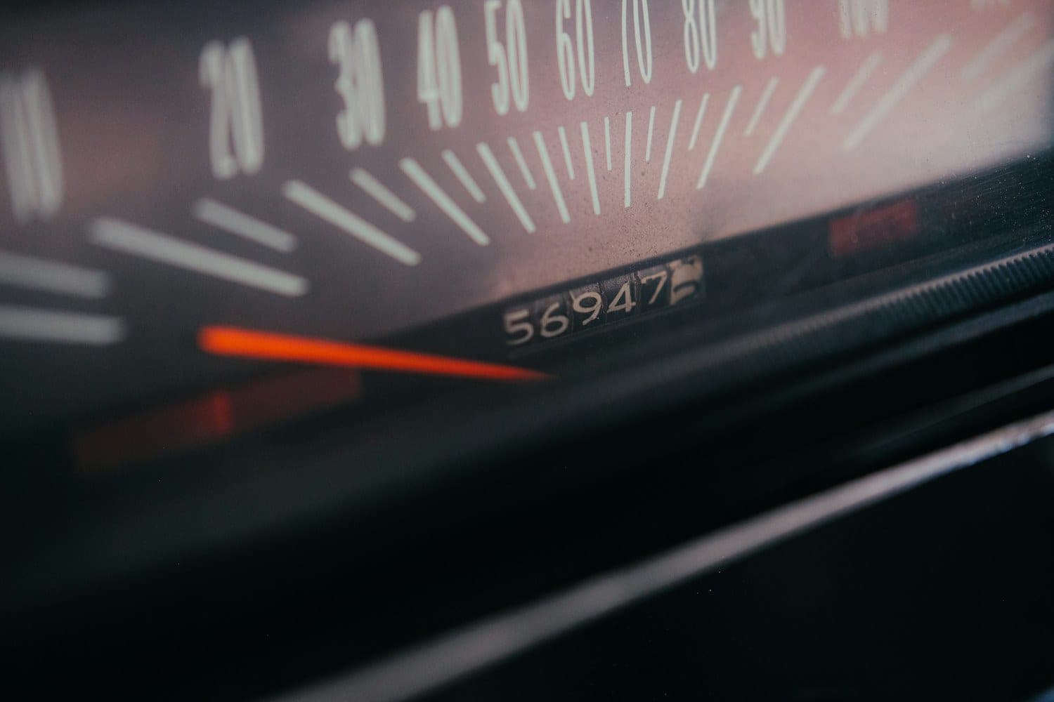Odometer and speedometer close-up Close-up of an analog odometer showing 56,947 miles below a red speedometer needle