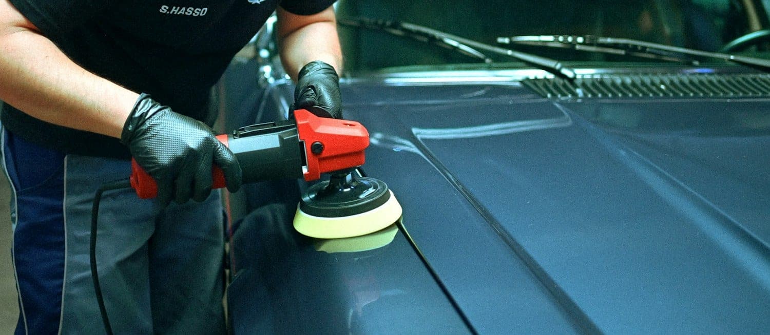 Machine polishing a car hood Detailer polishing a car hood with an orbital machine polisher